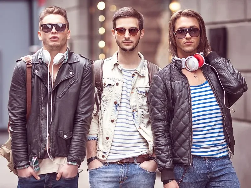 Três jovens com roupas de rua posando na calçada